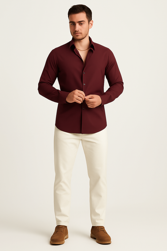 Man wearing a burgundy men's classic long sleeve button-down shirt with white pants and brown shoes, standing against a plain background.